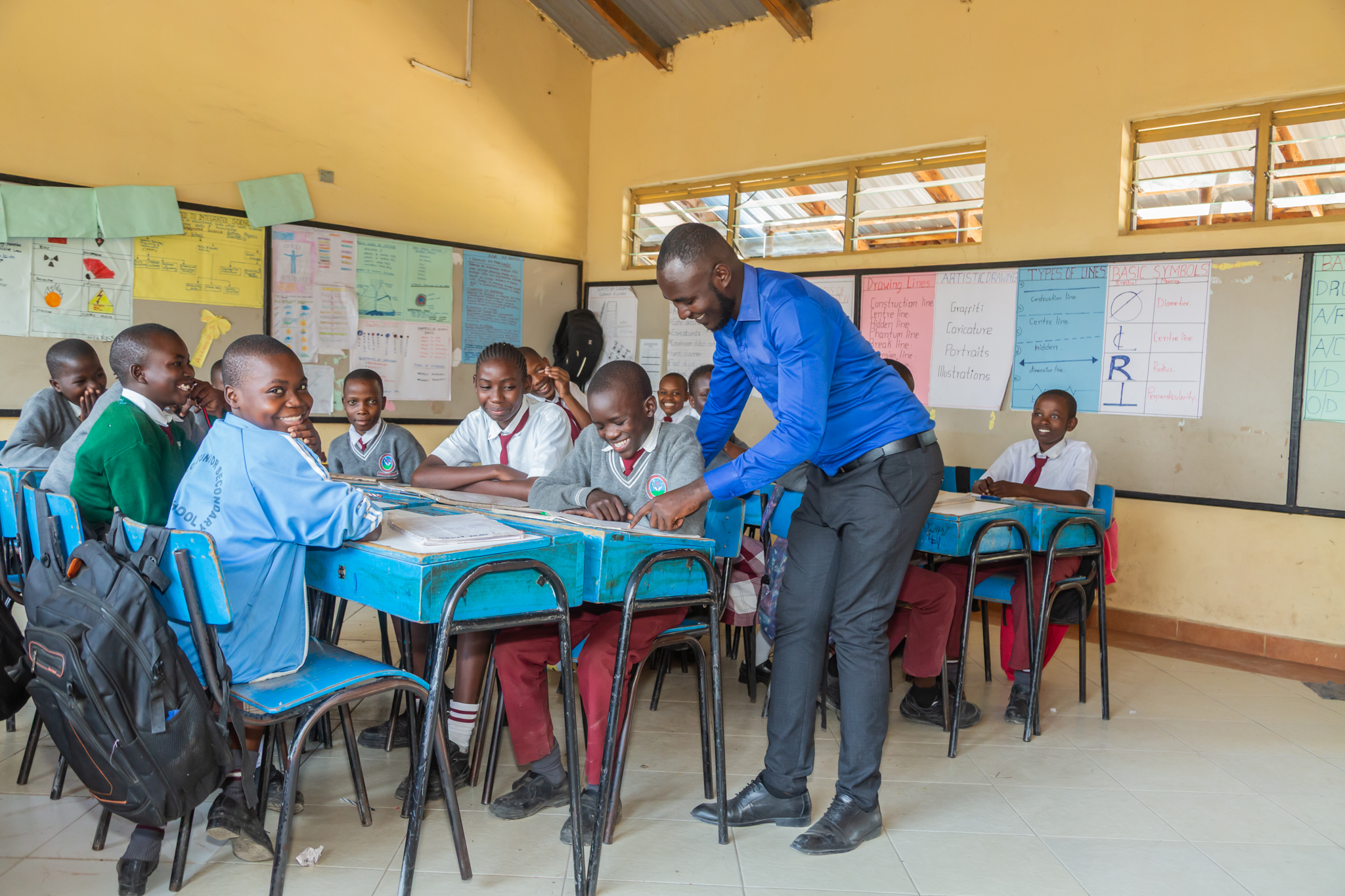 A group of smiling students and a teacher in a classroom